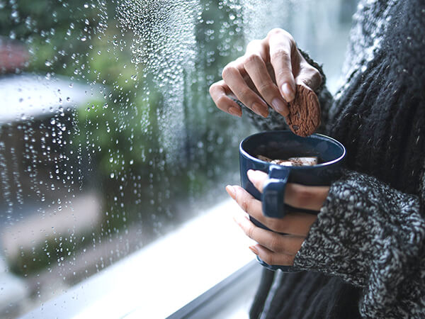 A window with condensation and cup of hot drink